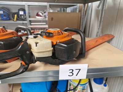 plusieurs tronçonneuses posées sur une étagère dans un magasin, avec une étiquette de prix