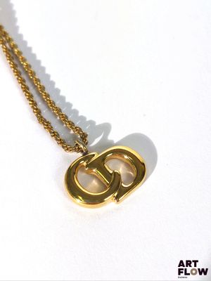 un collier en or sur lequel est gravée la lettre « g »