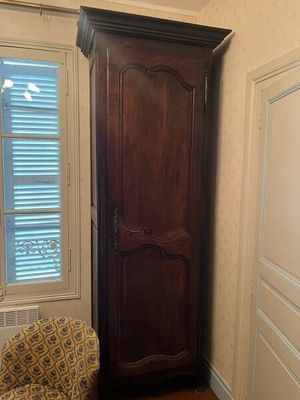 une chaise dans un coin de la pièce, à côté d'une grande armoire en bois