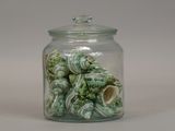 a glass jar filled with sea shells on a white surface