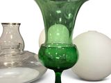 a green glass vase and a white egg on a table