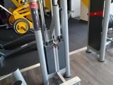 a gym room with a row of machines and a yellow wall