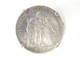 an old silver coin with an image of a woman and two men on it