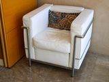 a white chair with a pillow on it in front of a cabinet