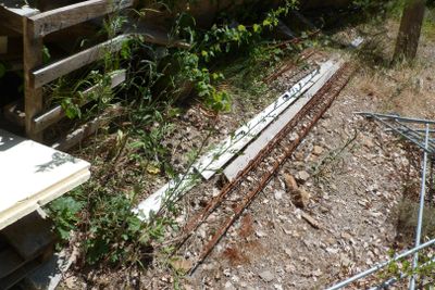a broken piece of wood on the ground next to a fence