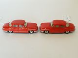 two red toy cars sitting next to each other on a table