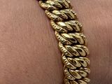 bracelet plaqué or au poignet d'une femme qui porte un bracelet à maillons en or