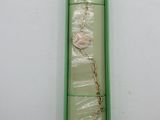 a green box with a necklace in it on a white surface