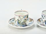 two cups and saucers sitting on a white table