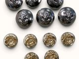 six boutons en verre noir et doré sur une surface blanche