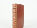 un vieux livre à la couverture en cuir marron posé sur une surface blanche