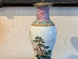 a vase sitting on a wooden table with a painting on the wall behind it