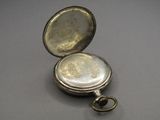 a small silver pocket watch with a key in it