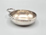 a silver bowl with a handle on a white surface