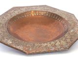 a rusted metal ashtray on a white surface