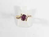 un gros plan d'une bague sertie d'une pierre rouge et de diamants