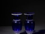 two blue glass vases sitting on a table