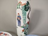 a vase with a painting on it next to a plate with a bowl on it