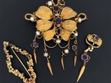 un gros plan sur une broche en or accompagnée d'un assortiment de bijoux