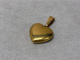 a small gold heart pendant on a white surface