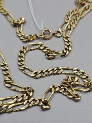 un gros plan sur un collier et un bracelet en chaîne d'or posés sur une table