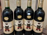 four bottles of wine are lined up on a wooden table