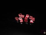 three pieces of red crystal sitting on top of a black surface
