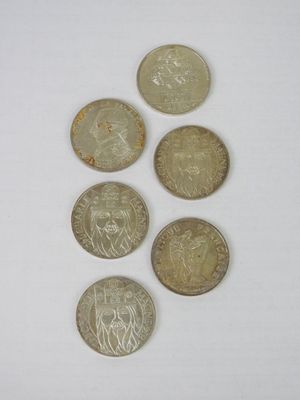 six different coins are arranged in a row on a white surface