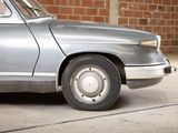 a silver car that is parked in front of a brick wall