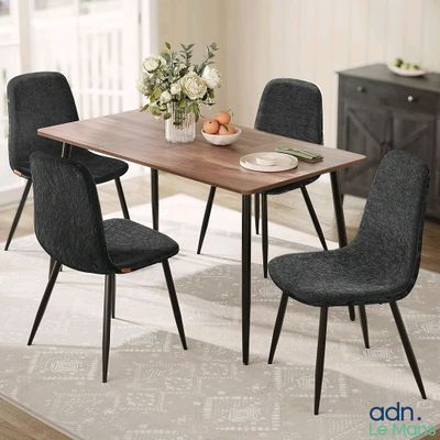 une table à manger avec quatre chaises et une corbeille de fruits posée dessus