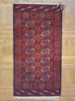 un tapis rouge posé sur un parquet, près d'un mur en bois