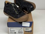 pair of children ' s black shoes on top of a cardboard box