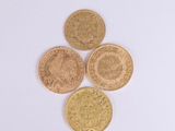 four different types of gold coins on a white surface
