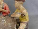 two figurines of men sitting at a table playing cards