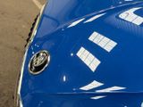 a close up of a blue car parked in a parking lot
