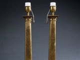 a pair of brass candles on stands with a rope