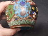 a person holding a vase with a colorful design on it