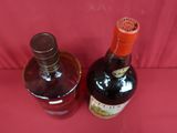 two bottles of wine sitting on a red surface