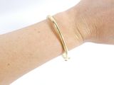 a woman ' s arm with a gold bracelet on it