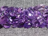 de très jolis cristaux violets posés sur un tissu gris