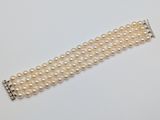 un gros plan d'un bracelet de perles blanches posé sur une surface blanche