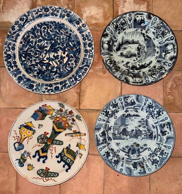 quatre assiettes bleues et blanches ornées de motifs, posées sur un sol carrelé