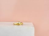 une bague en or sertie d'un diamant, posée sur un bloc de marbre blanc