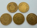 quatre types différents de pièces d'or reposant sur une surface blanche