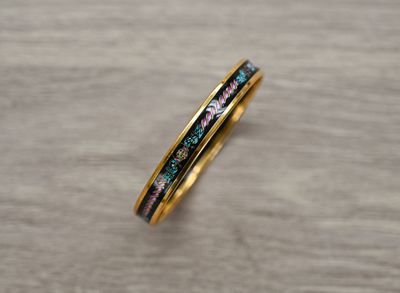 un gros plan sur une bague en or sertie de diamants bleus et roses