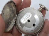a person holding a silver pocket watch in their hand