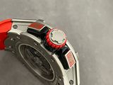 someone is holding a red watch on a gray surface