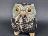 a ceramic owl that is sitting on a black surface