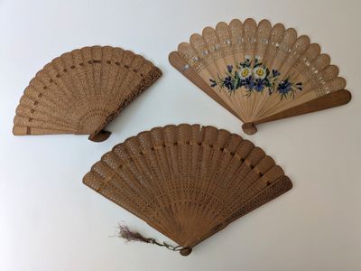 trois éventails en bois ornés de motifs floraux sur un fond blanc