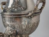 a silver vase with a dragon handle on top of it